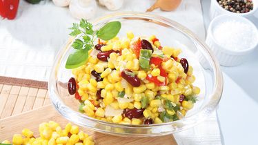 Glasschüssel mit frischem Maissalat vom Foodservice, angereichert mit Bohnen, Paprika und Zwiebeln