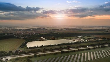 Luftaufnahme einer großen Gewächshausanlage und umliegender Felder bei Sonnenuntergang